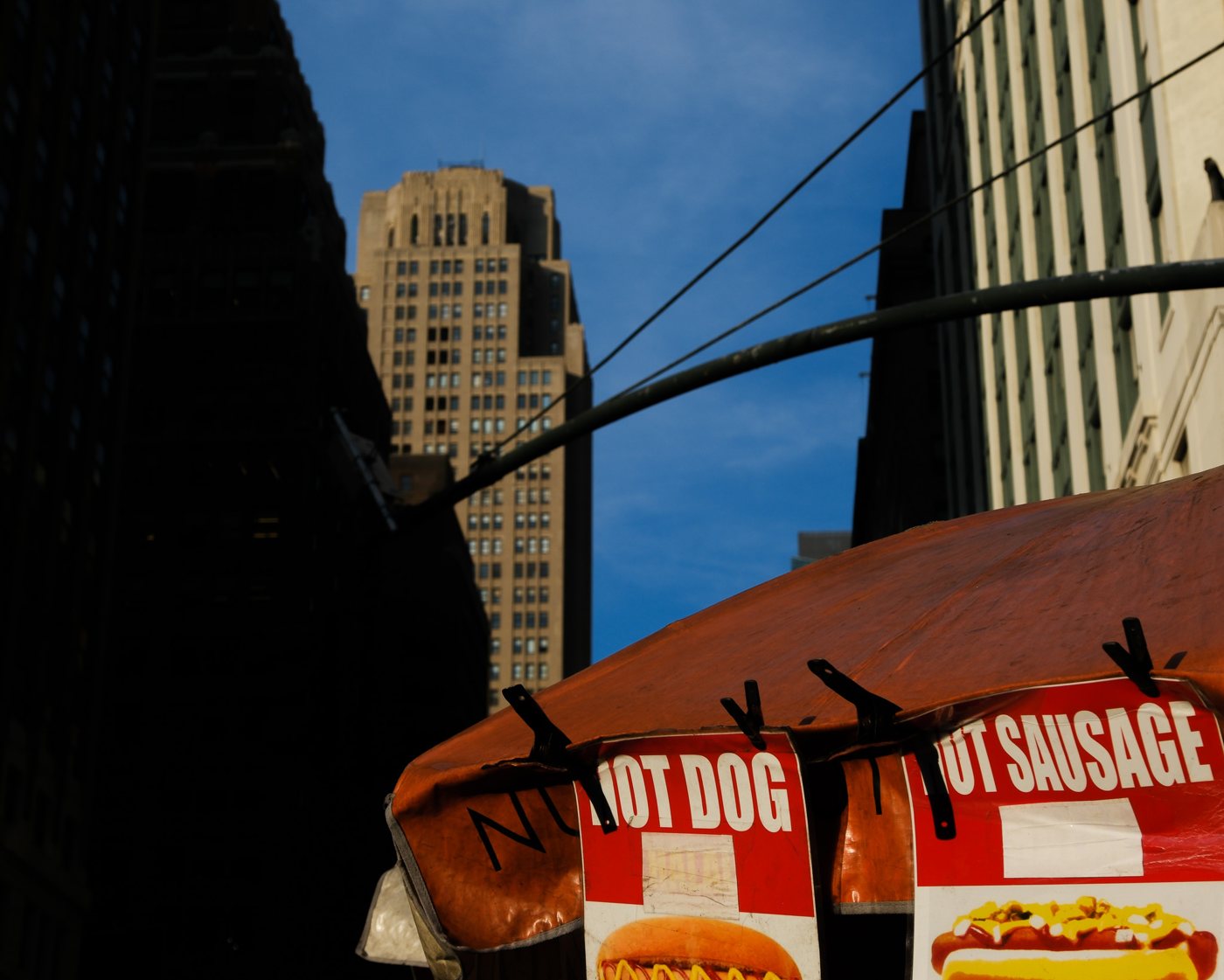 A hot dog cart under Manhattan towers