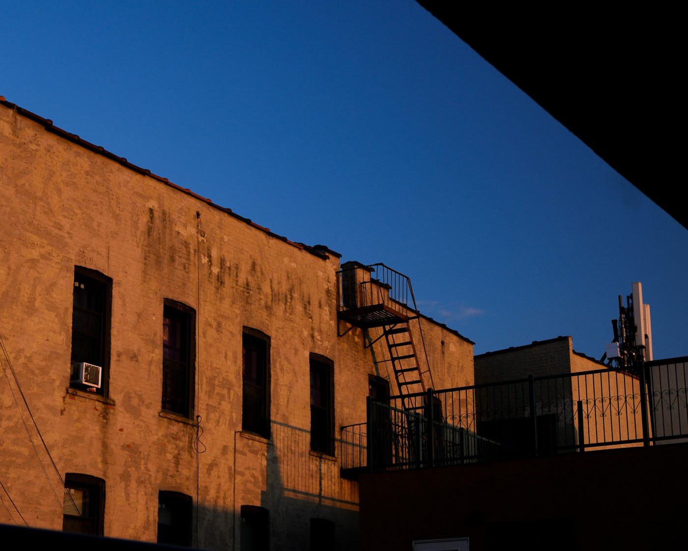 A brick building with a fire escape against a deep blue sky