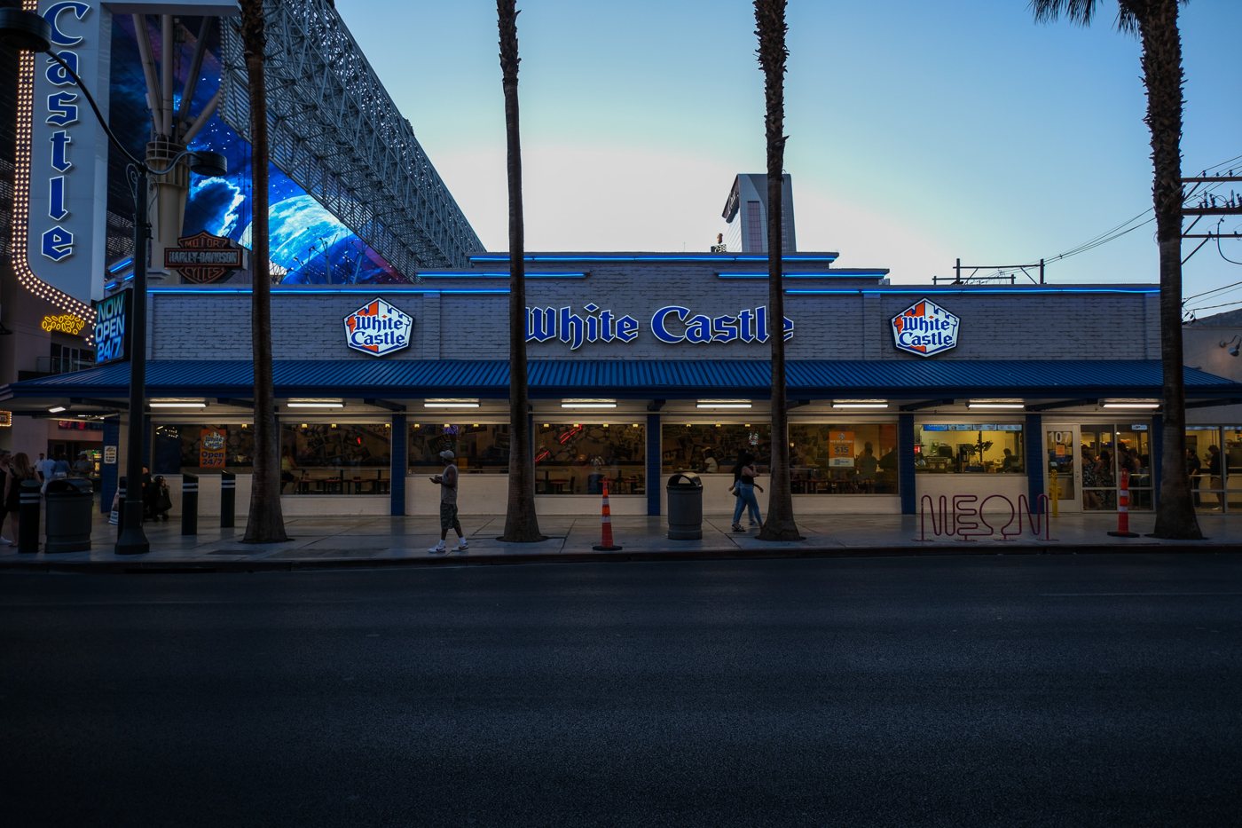 A neon-lit diner on Fremont Street at dusk, lined with palm trees